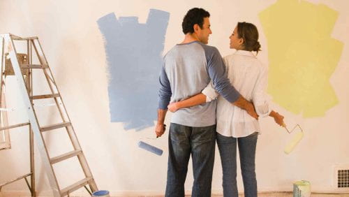 pareja abrazada pintando pared de dos colores